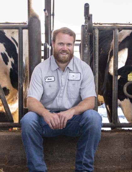 Brian Fiscalini sitting with dairy cows in barn